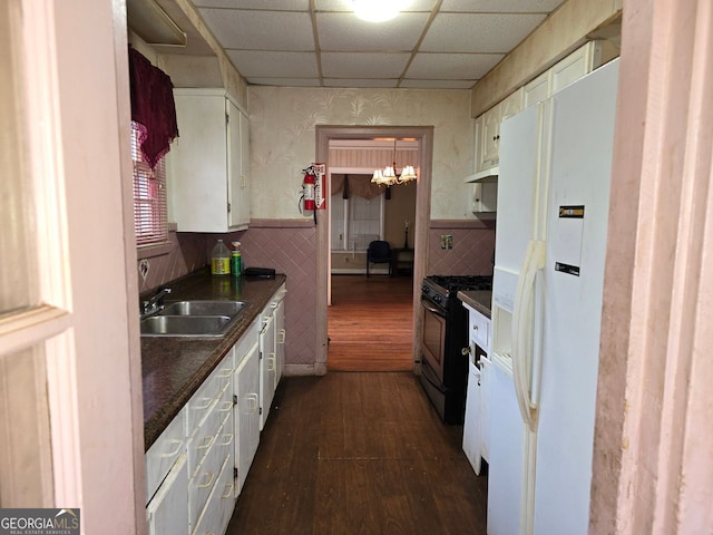 kitchen with sink, dark wood-type flooring, white refrigerator with ice dispenser, gas stove, and a drop ceiling