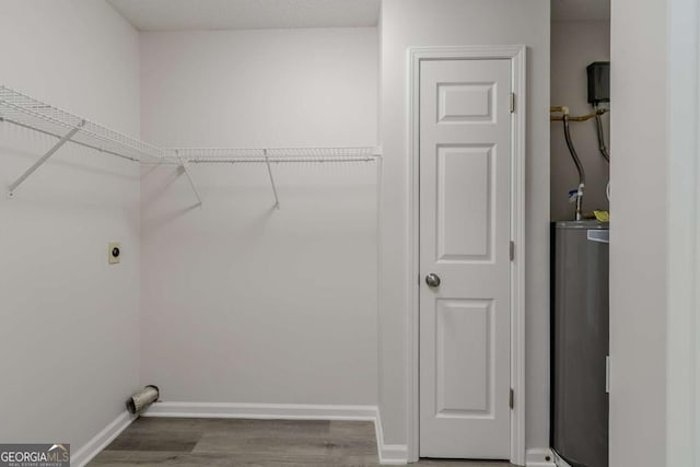 laundry area featuring dark wood-type flooring, water heater, and electric dryer hookup