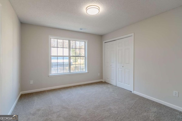 unfurnished bedroom with a closet, a textured ceiling, and carpet floors