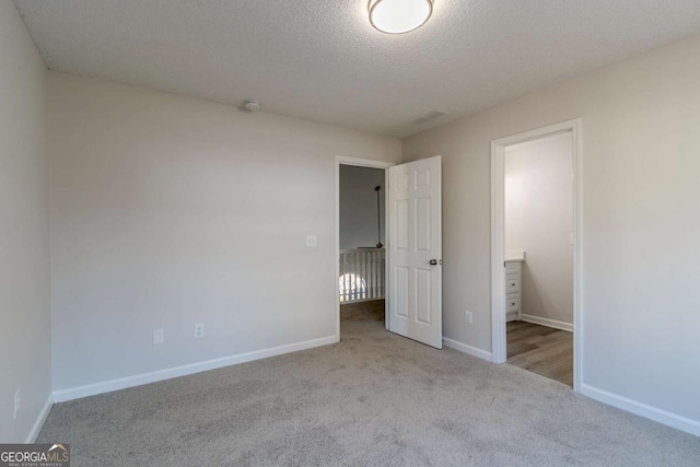 unfurnished bedroom with light colored carpet and a textured ceiling