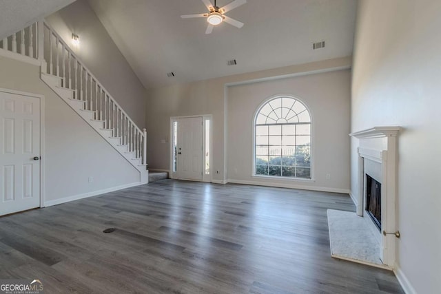 unfurnished living room featuring a towering ceiling, ceiling fan, and dark wood-type flooring