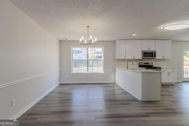 kitchen with appliances with stainless steel finishes, hanging light fixtures, white cabinets, and kitchen peninsula