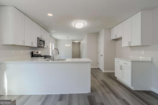 kitchen featuring appliances with stainless steel finishes, white cabinetry, sink, and kitchen peninsula