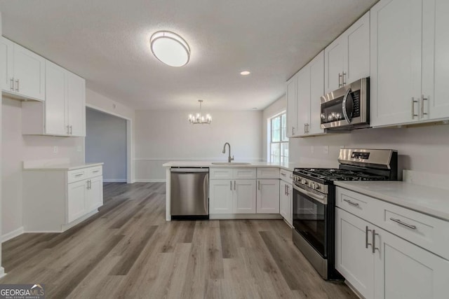 kitchen with sink, decorative light fixtures, white cabinetry, and appliances with stainless steel finishes