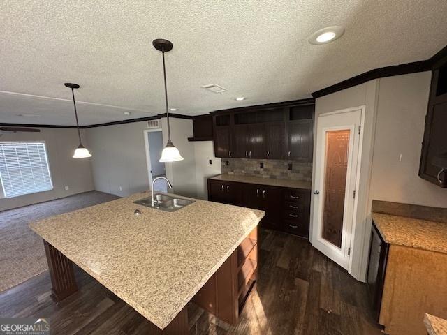 kitchen with a kitchen island with sink, pendant lighting, and dark brown cabinets