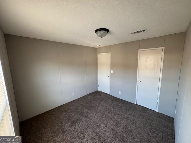 unfurnished bedroom featuring a textured ceiling and carpet