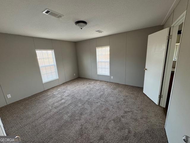 carpeted empty room featuring a textured ceiling