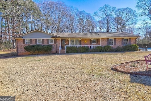 ranch-style home featuring covered porch and a front lawn