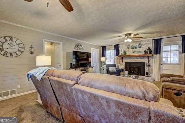 carpeted living room with a textured ceiling, ceiling fan, a brick fireplace, and wood walls