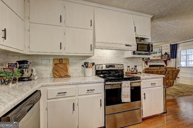 kitchen with light stone countertops, light hardwood / wood-style flooring, stainless steel appliances, tasteful backsplash, and white cabinets