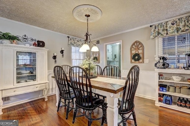 dining room featuring a textured ceiling, ornamental molding, and dark hardwood / wood-style flooring