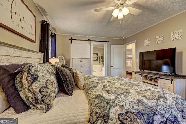 bedroom with ensuite bath, a barn door, ornamental molding, ceiling fan, and a textured ceiling