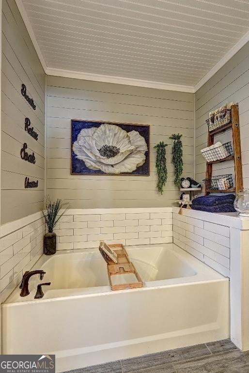 bathroom featuring hardwood / wood-style flooring, a bath, and crown molding