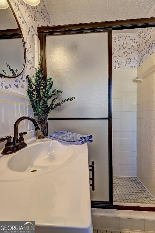 bathroom featuring a shower with shower door and sink