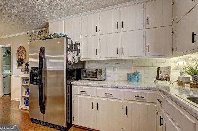 kitchen featuring white cabinets, washer / clothes dryer, and stainless steel fridge