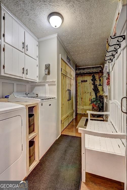 laundry area featuring a textured ceiling, cabinets, independent washer and dryer, ornamental molding, and hardwood / wood-style floors