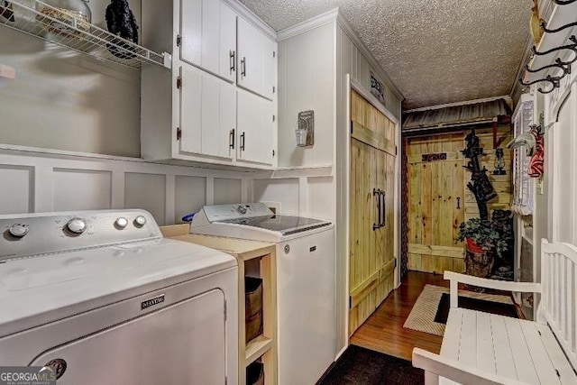 washroom featuring a textured ceiling, cabinets, ornamental molding, separate washer and dryer, and dark hardwood / wood-style flooring