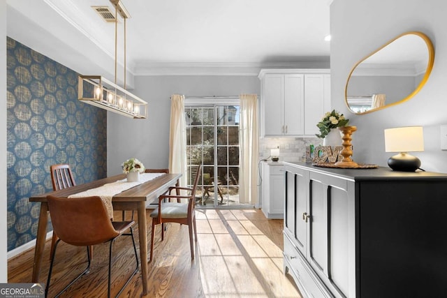 dining area featuring ornamental molding and light hardwood / wood-style flooring