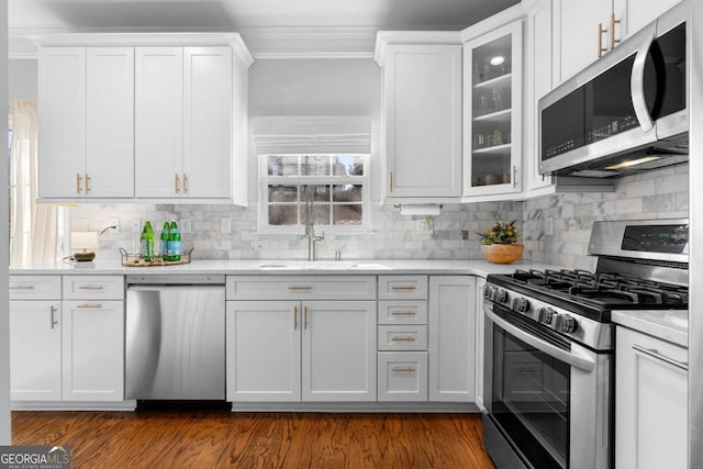 kitchen with stainless steel appliances, white cabinetry, sink, and tasteful backsplash