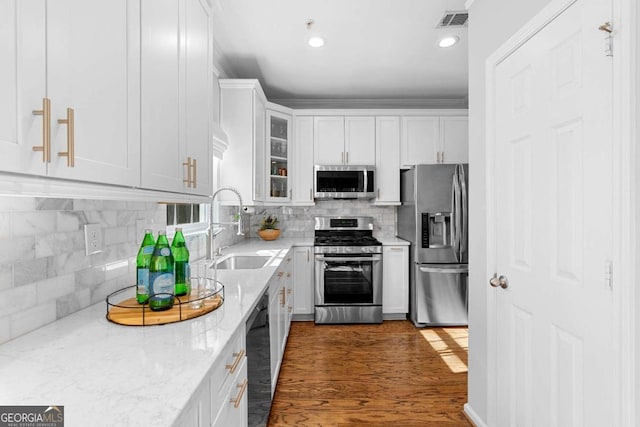 kitchen featuring light stone countertops, stainless steel appliances, decorative backsplash, white cabinetry, and sink