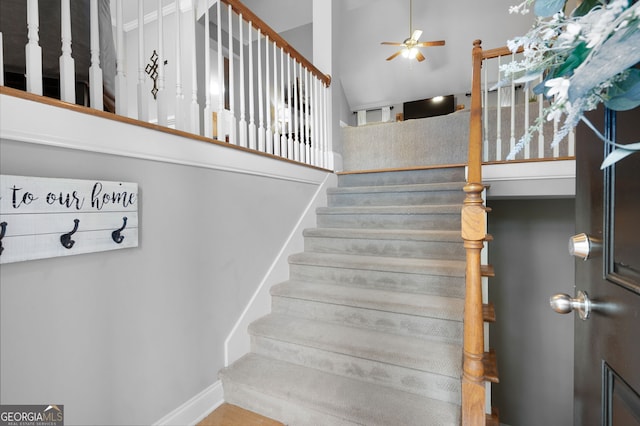 stairway featuring ceiling fan and a high ceiling