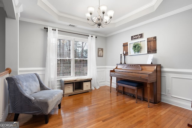 sitting room featuring light hardwood / wood-style floors, a tray ceiling, and ornamental molding