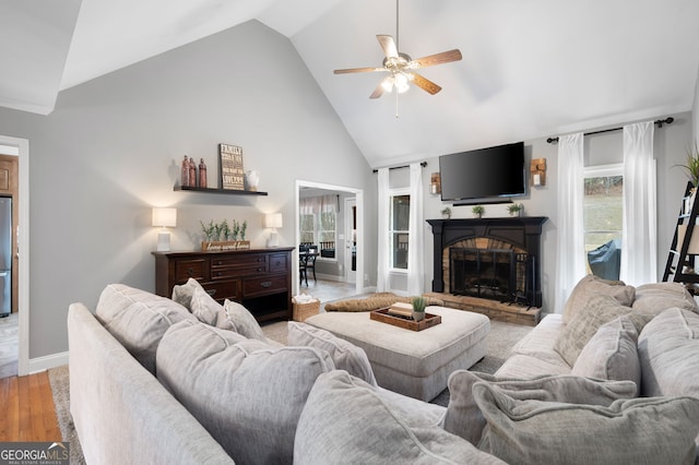 living room featuring light hardwood / wood-style floors, high vaulted ceiling, and ceiling fan