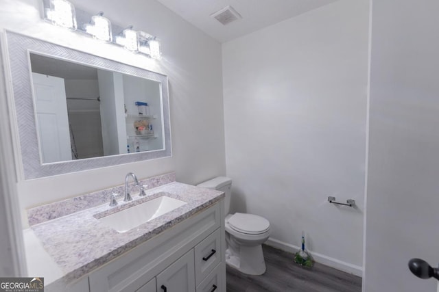 bathroom with toilet, hardwood / wood-style flooring, and vanity