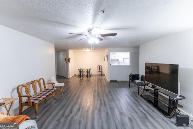 living area with a textured ceiling, dark hardwood / wood-style flooring, and ceiling fan