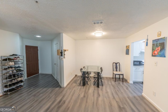 dining room with a textured ceiling and wood-type flooring