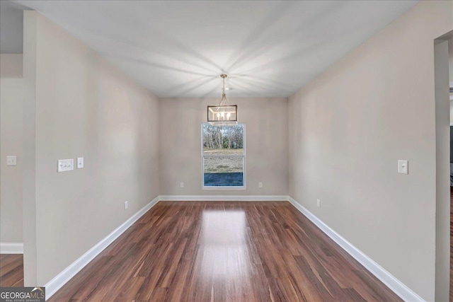 unfurnished dining area featuring an inviting chandelier and dark hardwood / wood-style flooring