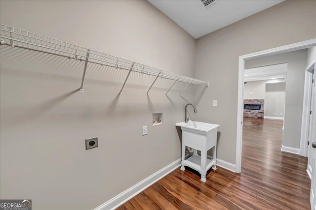 washroom featuring dark wood-type flooring, hookup for an electric dryer, hookup for a washing machine, and a fireplace