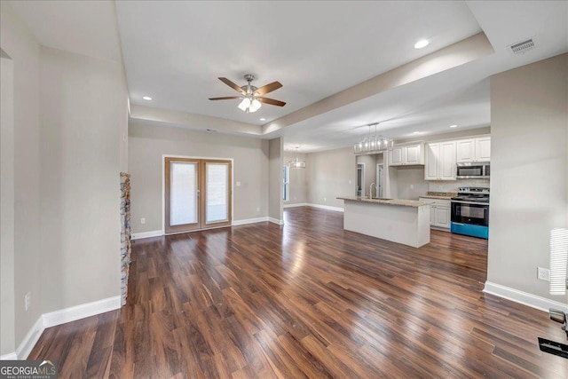 unfurnished living room with dark wood-type flooring, a raised ceiling, ceiling fan, and sink