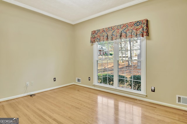 spare room with a wealth of natural light, ornamental molding, and hardwood / wood-style flooring