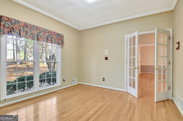 unfurnished room featuring light hardwood / wood-style floors, a textured ceiling, ornamental molding, and french doors