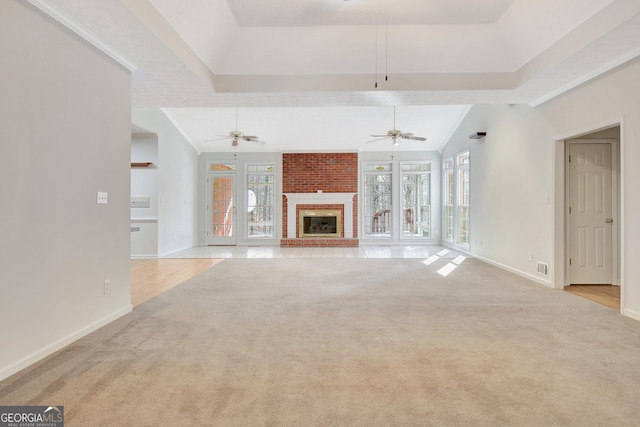 unfurnished living room featuring ceiling fan, light colored carpet, french doors, and a fireplace