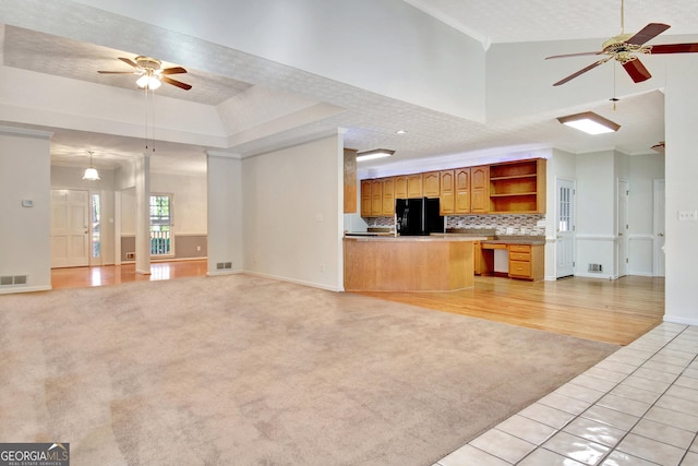 unfurnished living room featuring ceiling fan, light colored carpet, and a raised ceiling