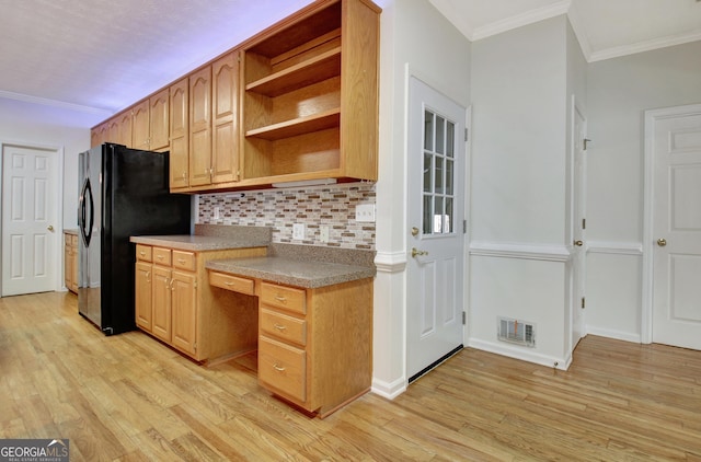 kitchen featuring black fridge, ornamental molding, light hardwood / wood-style floors, and backsplash