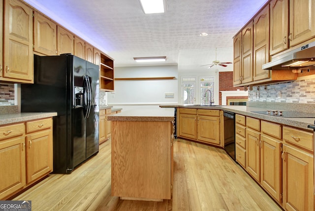 kitchen featuring a center island, black appliances, light hardwood / wood-style floors, sink, and backsplash