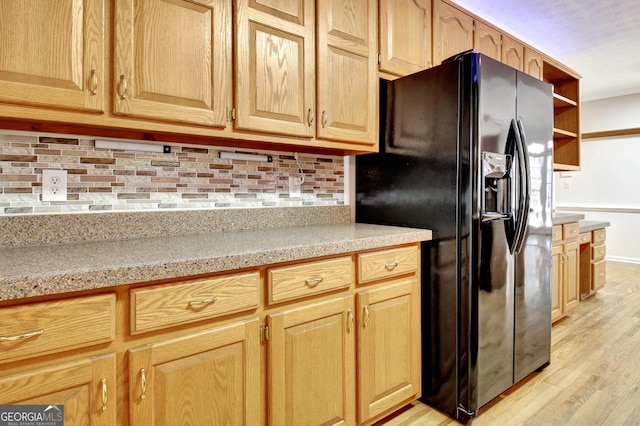 kitchen with black fridge, tasteful backsplash, and light wood-type flooring