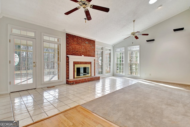 unfurnished living room featuring ceiling fan, a brick fireplace, light tile patterned flooring, and lofted ceiling