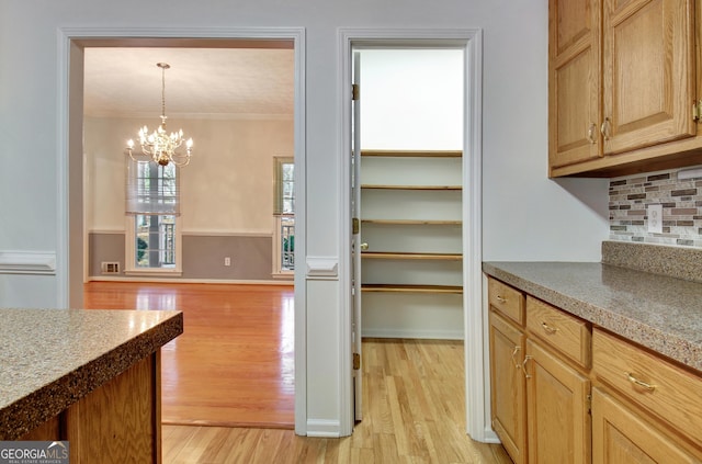 kitchen with an inviting chandelier, decorative backsplash, light brown cabinetry, hanging light fixtures, and light hardwood / wood-style flooring