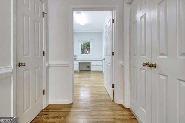 corridor featuring light wood-type flooring and ornamental molding