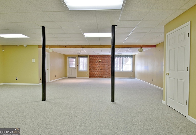 basement featuring light carpet, a drop ceiling, and a wealth of natural light