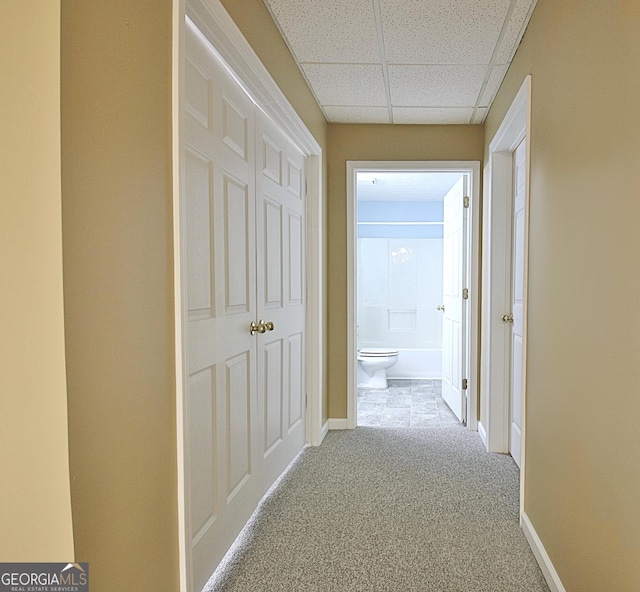 hallway featuring a paneled ceiling and light colored carpet