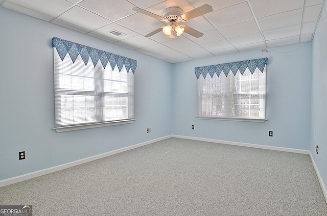 carpeted empty room with ceiling fan, a paneled ceiling, and a wealth of natural light