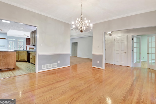 interior space with light wood-type flooring, ornamental molding, ceiling fan with notable chandelier, and sink