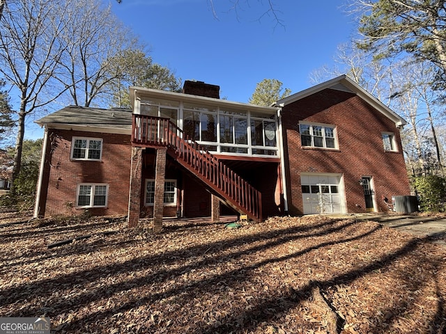 rear view of house with a sunroom, central air condition unit, and a garage