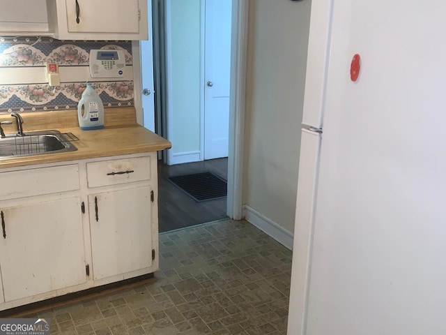 kitchen featuring sink, white cabinets, and white fridge