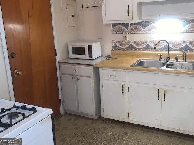 kitchen with white appliances, electric panel, white cabinetry, and sink